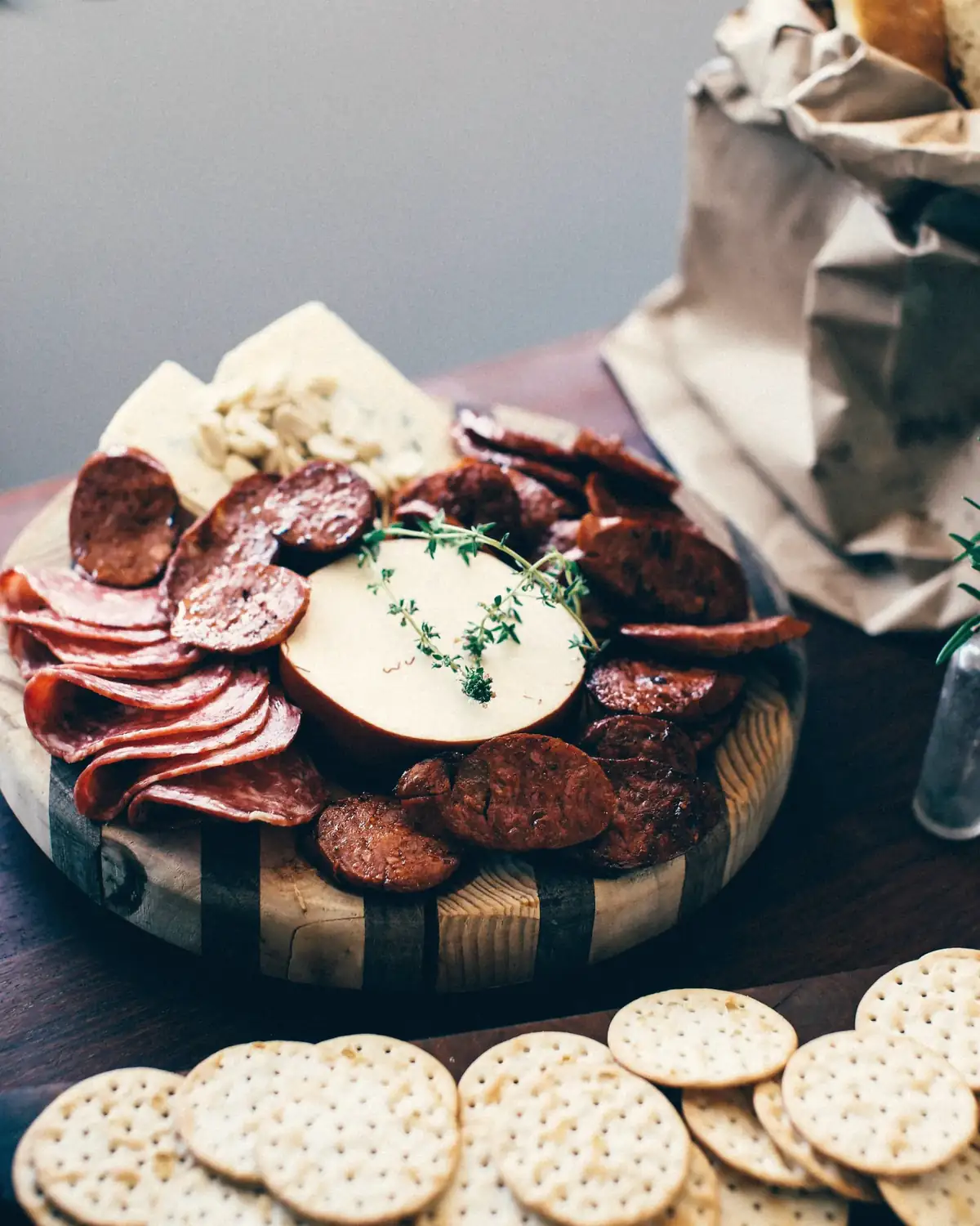Een houten plank met worst, kaas en crackers