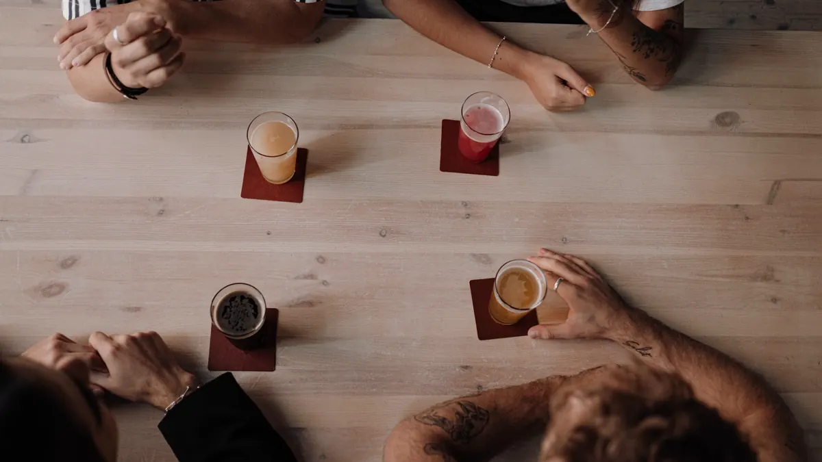 Een groep rond een houten tafel met glazen, van boven gezien
