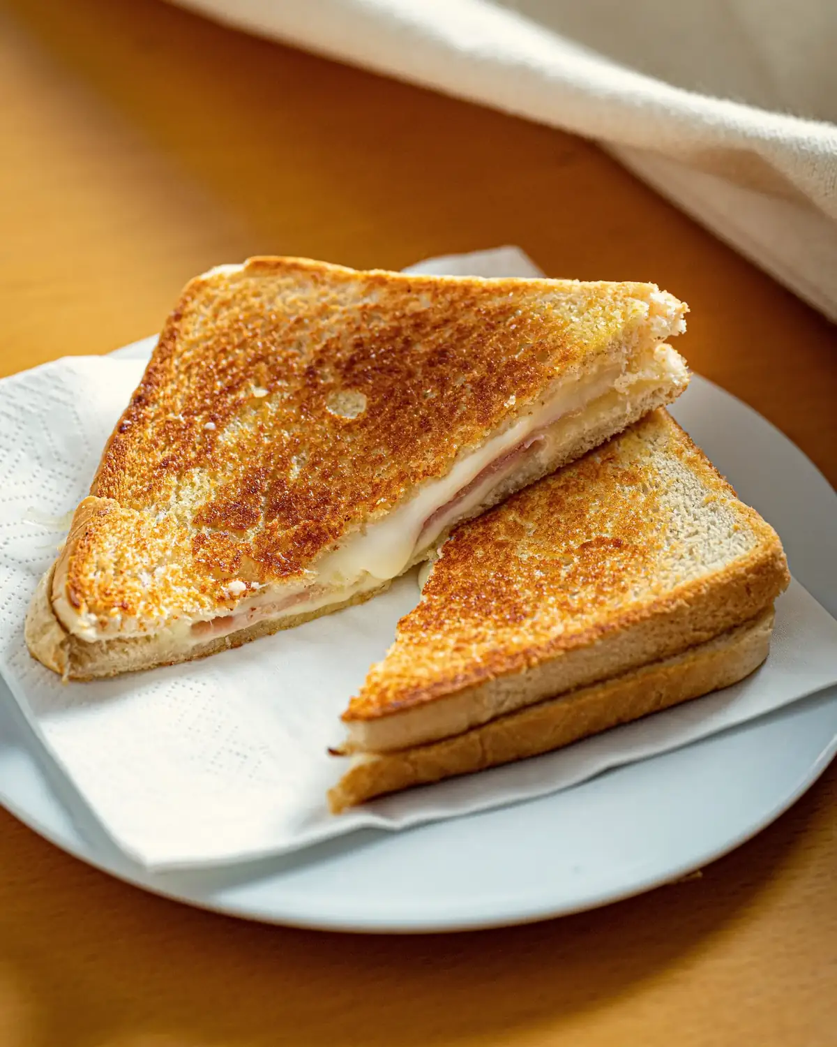 Een tosti ham en kaas, doormidden gesneden, op een bord